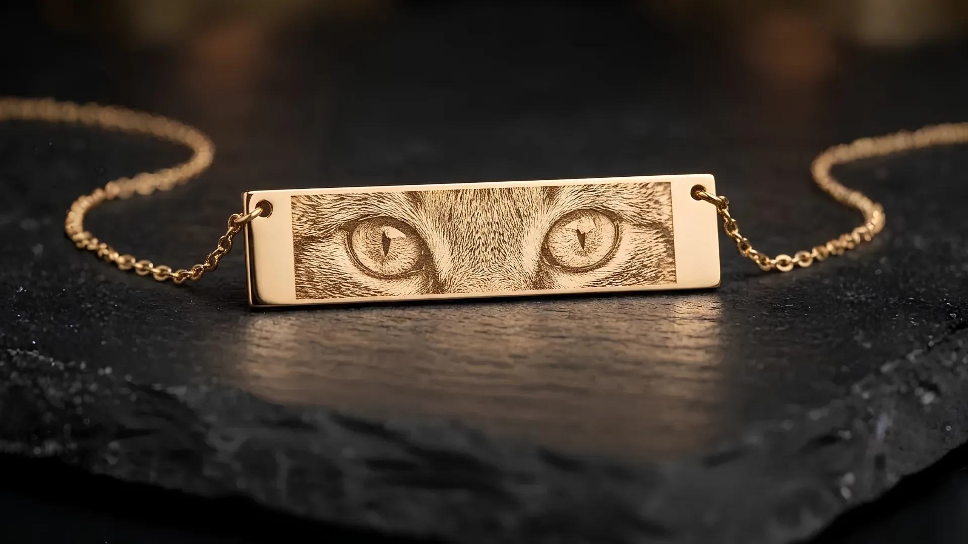 Close-up of engraved eyes on a gold bar pendant, showing pupil and lash detail